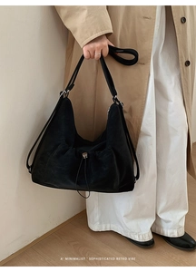 Detail of black suede drawstring shoulder bag with silver metal bead and retro vibe