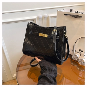 Detail of glossy black quilted shoulder bag featuring CC-style metal buckle and fine strap