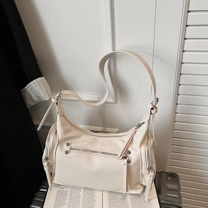Close-up of cream white shoulder bag featuring industrial zippers and metallic rivets