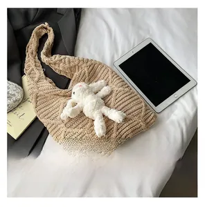 Detailed close-up of beige knit tote bag texture with cute plush rabbit doll charm
