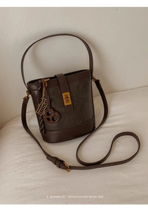 Detail of vintage matte leather bucket bag in dark brown with gold turn-lock and strap