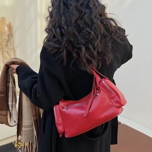 Detailed view of a red leather shoulder bag with zipper accents worn by a model