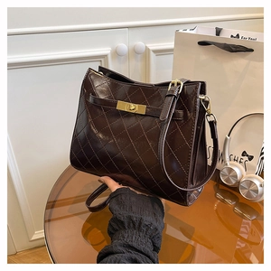 Detail of chocolate brown quilted bag with a gold twist lock and diamond stitching