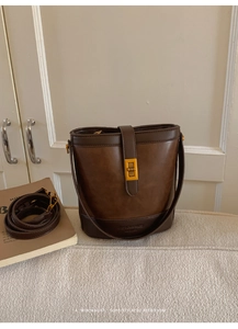 Detail of vintage dark brown bucket bag featuring gold twist lock and leather texture