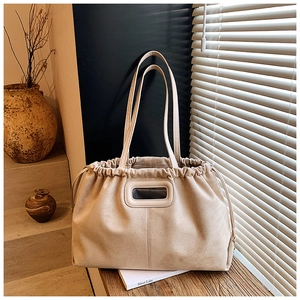 Détail d'un sac cabas en daim terreux avec cordon de serrage dans un décor minimaliste