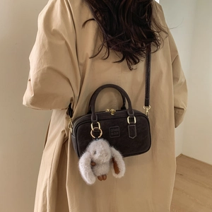 Detail of dark brown vintage Boston bag with gold zipper and plush rabbit charm
