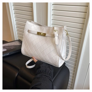 Detail of cream quilted shoulder bag featuring glossy PU texture and gold twist lock