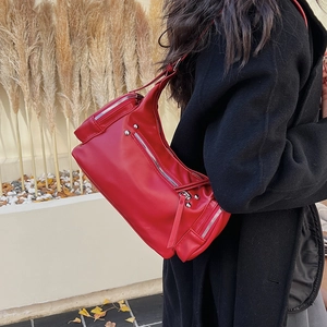 Detail of red faux leather shoulder bag with silver studs and long zipper pulls