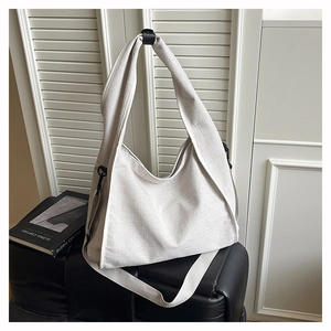 Detail of a large cream canvas hobo bag with wide strap and black metal buckles