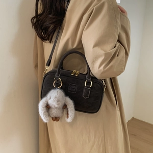Brown vintage Boston bag detail with plush bunny charm and golden hardware strap