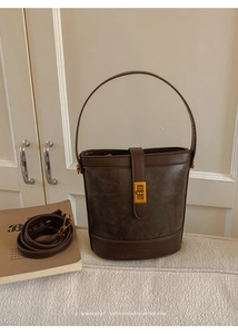 Detail of dark brown vintage bucket bag with matte texture and gold buckle lock