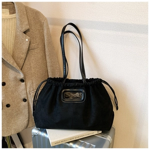Détail du sac cabas en daim noir avec cordon de serrage sur valise argentée avec veste