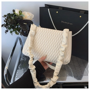 Close-up of quilted cream shoulder bag with stylish scrunchie handle and rhombus pattern