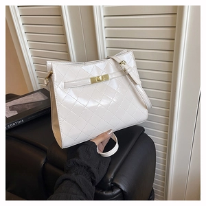 Close-up of white quilted leather shoulder bag featuring gold rectangular turn-lock closure