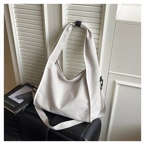 Detail of off-white canvas hobo bag with wide strap hanging against white shutters