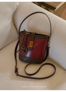 Detail of burgundy matte bucket bag with gold twist lock and vintage contrast stitching