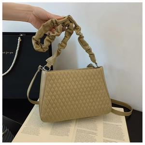 Close-up of khaki quilted crossbody bag with pleated handle and metal ring detail