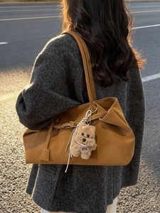 Caramel brown suede tote bag with plush puppy charm and soft shoulder strap in outdoor light