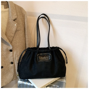 Détail du grand sac cabas en suédine noire avec fermeture à cordon sur valise