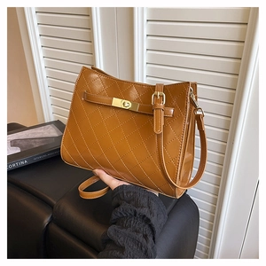 Close-up of brown quilted leather shoulder bag featuring gold buckle and metallic lock