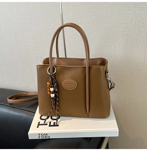 Detailed macro of brown pebble leather bucket bag with fringe tassel and logo patch