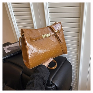 Close-up of brown quilted leather handbag with gold metal clasp and trapezoid design