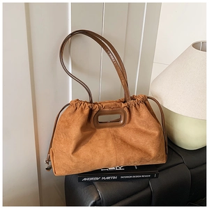Détail d'un sac cabas en daim marron avec bandoulière en cuir et pendentif coeur