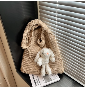 Macro shot of beige chunky knit tote bag texture with cute plush bunny charm detail
