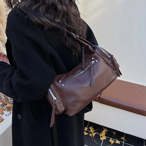 Detail view of coffee leather shoulder bag with vintage silver zippers and rivets