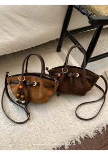 Detailed close-up of retro suede tote bag texture with leather handle and colorful beads