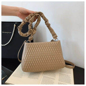 Macro detail of khaki quilted PU leather bag with pleated handle and fine shoulder strap