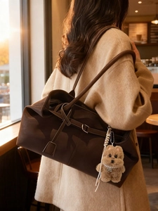 Brown leather tote bag with knot strap and dog pendant in a cozy cafe setting