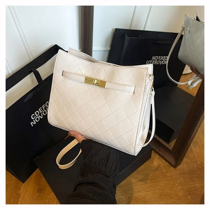 Close-up of cream quilted handbag featuring elegant gold twist lock and fine stitching