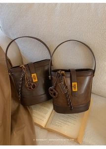 Close-up of brown vintage leather bucket bags with metal clasps and woven charms