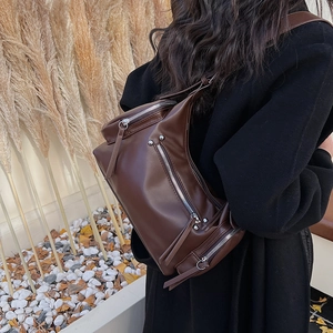Detail of dark brown matte leather crossbody bag with silver zippers and studs