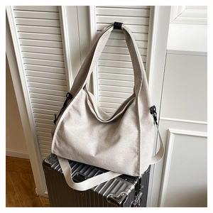 Detail of light beige woven tote bag texture and wide strap on silver suitcase