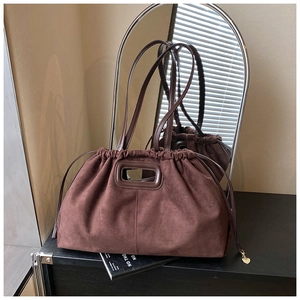 Détail du sac cabas en daim marron foncé avec fermeture à cordon et pendentif cœur doré