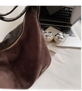 Détail du sac à bandoulière marron foncé avec texture en daim et accents dorés