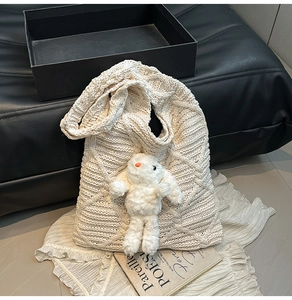 Detail of white knit tote bag with large diamond weave texture and cute bunny plush charm