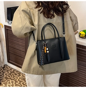 Detail of black textured leather bucket bag with decorative beads on a model