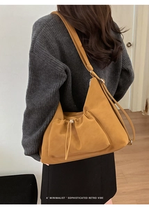 Detail of minimalist mustard suede shoulder bag featuring drawstring buckle and retro vibe