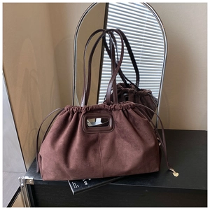Détail du cabas en daim marron foncé avec fermeture à cordon et pendentif cœur doré