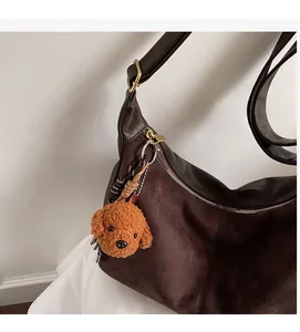 Détail du sac bandoulière en daim marron foncé avec un joli pendentif caniche en peluche