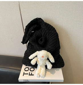 Close-up of black knitted tote bag with cute white plush rabbit doll charm