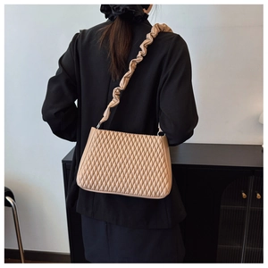 Detail of beige quilted shoulder bag with unique ruched strap and stylish rhombus pattern