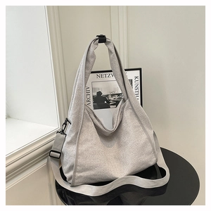 Detailed view of the large grey crossbody bag with adjustable wide strap on a table