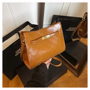 Detailed close-up of brown quilted leather texture and gold twist lock on shoulder bag