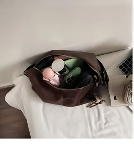 Intérieur spacieux d'un cabas en daim marron foncé montrant les essentiels et le zip en métal
