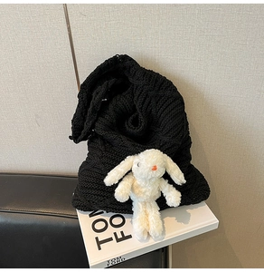 Detail of black knit tote bag with rabbit doll and premium cable weave texture