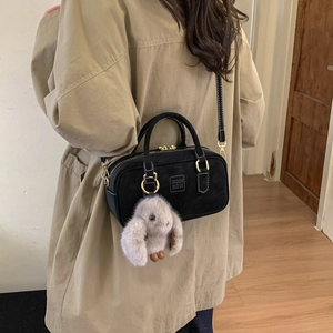 Detail of black Boston bag with COIN 2DN logo and cute long-eared bunny plush charm